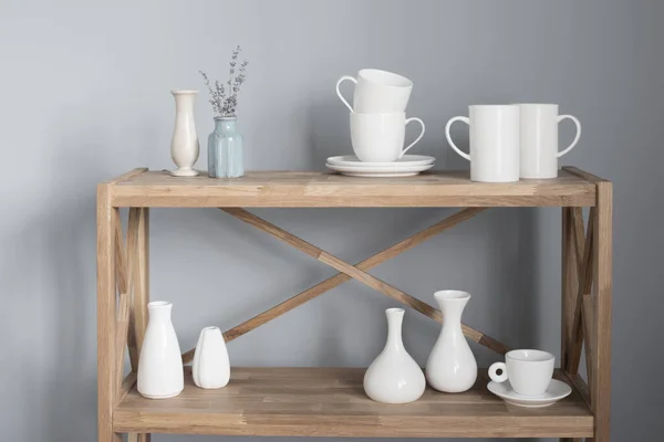 灰色背景的木制架子上的白色杯子和花瓶 — 图库照片