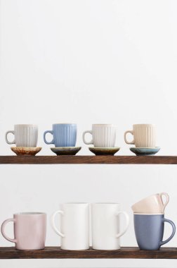 Beyaz arkaplanda ahşap raflarda renkli bardaklar