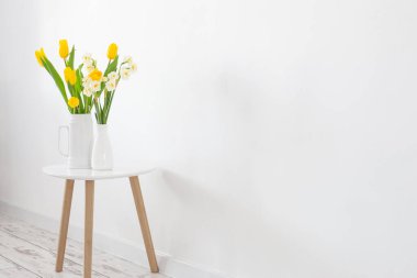 Beyaz arkaplanda vazoda beyaz ve sarı bahar çiçekleri