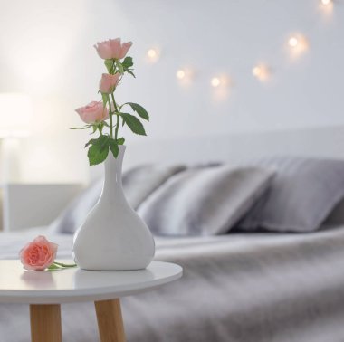 Yatak odasındaki masada vazoda pembe güller.