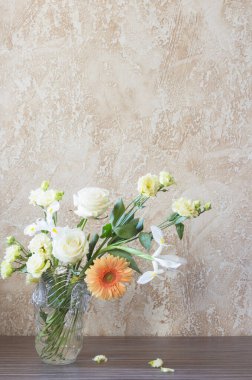 Arka plandaki masada cam vazoda bir buket.