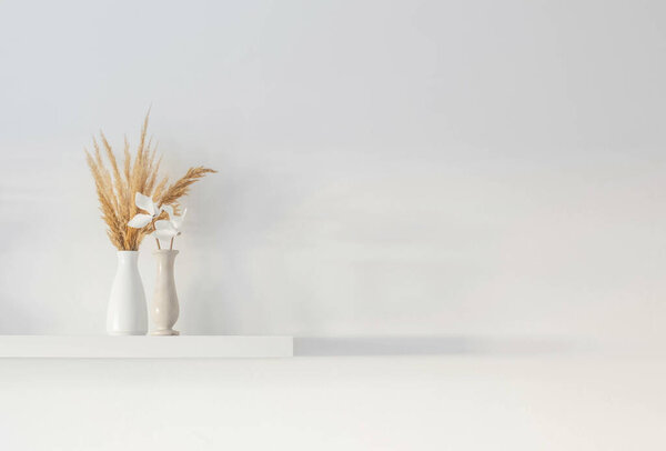 bouquet of dried wild flowers in white vase on wooden shelf on background white wall
