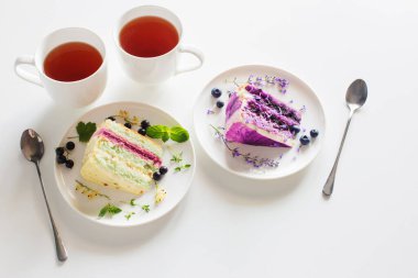 Çilekli kek ve beyaz masada iki fincan çay.