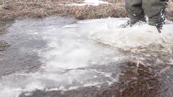 ブーツを着た男が丘から凍った水たまりに飛び込み — ストック動画