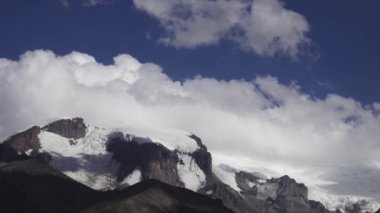 Bulutlar Elbrus 'un karla kaplı yamaçlarında süzülür