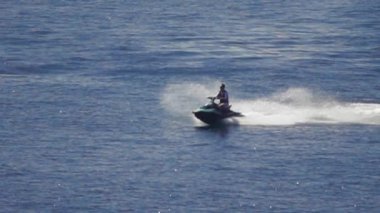 Havalı adam nehirde jet ski sürüyor.
