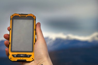 Akıllı telefon, dağın arka planında korunan ip68 'dir. Dağlarda kız gezisi