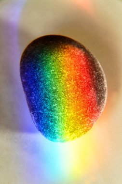 Zen stone in touch of rays of color. The concept of maximum joy from color