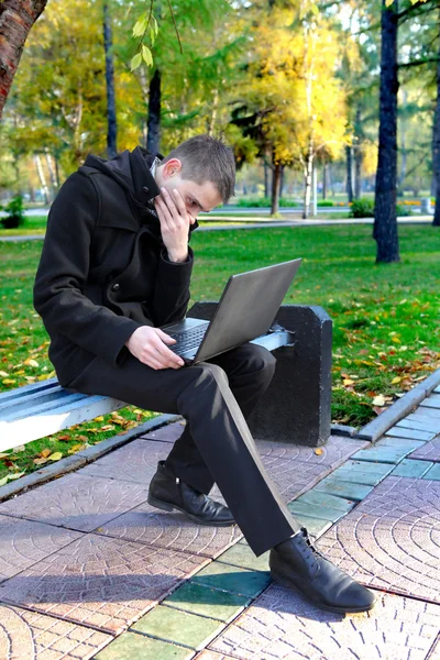 Человек с ноутбуком в парке — стоковое фото
