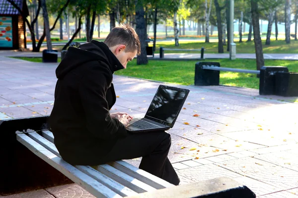 Homem trabalhando no laptop no parque — Fotografia de Stock