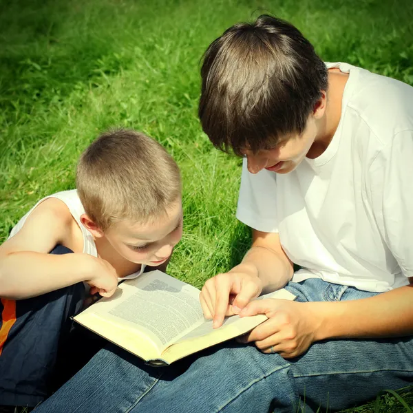 Adolescente y niño con un libro — Foto de Stock