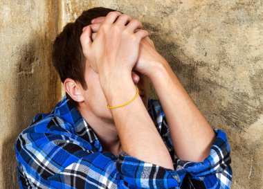 Üzgün genç adam, Yaşlı Duvar 'ın orada elleri olan bir yüzü gizliyor.