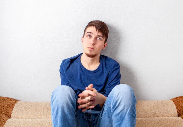 Smutný Mladý Muž Sedí Pohovce Domě Zdi — Stock fotografie