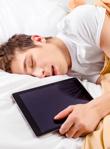 タブレットコンピュータでベッドで寝る若い男 — ストック写真
