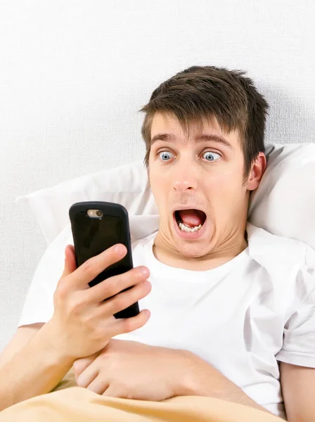 Genç Adamı Evdeki Yatakta Cep Telefonuyla Şok Etti — Stok fotoğraf