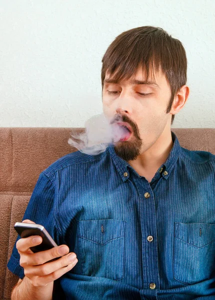 Człowiek Dmuchać Dym Papierosa Trzymać Telefon Komórkowy Kanapie Domu — Zdjęcie stockowe