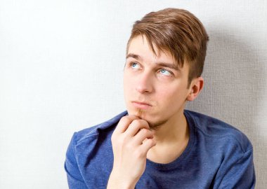 Genç adam duvarın yanındaki evde düşünüyor.