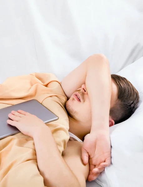 Jongeman Slapen Het Bed Met Een Tablet Computer — Stockfoto