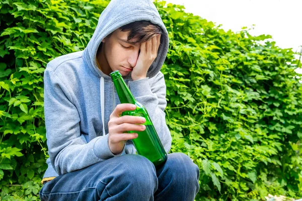 Sad Young Man Hoodie Hold Beer Bottle Green Leaves Background — Stockfoto