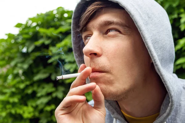 Mladý Muž Kouří Cigaretu Portrét Zelených Listech Pozadí Detailní — Stock fotografie