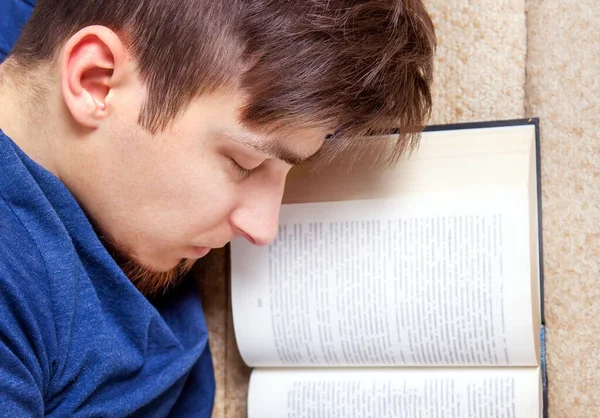 疲惫的年轻人带着翻开的书睡在沙发上 — 图库照片