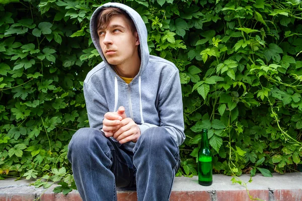Грустный Молодой Человек Капюшоне Бутылкой Пива Обочине Городской Улицы — стоковое фото