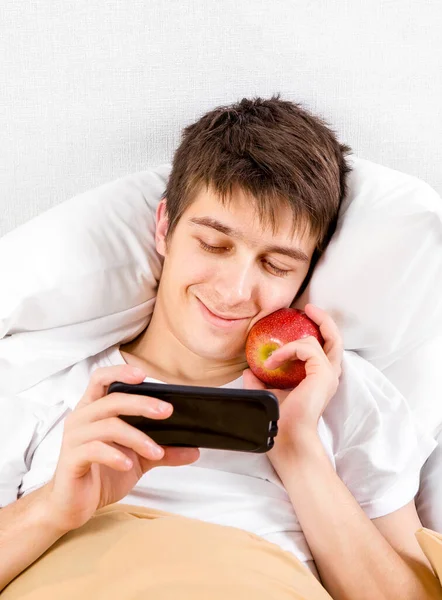 Щасливий Молодий Чоловік Яблуком Користується Телефоном Ліжку Вдома Стокове Фото
