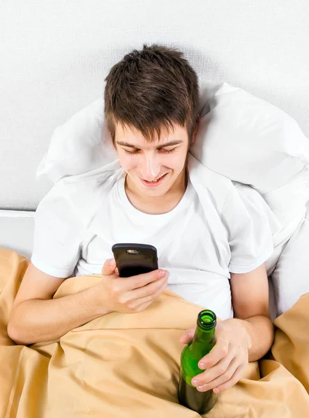 Junger Mann Mit Telefon Und Bierflasche Bett Stockbild