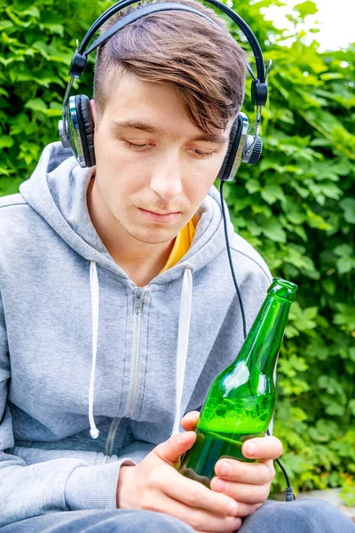 Jovem Triste Fones Ouvido Com Uma Cerveja Fundo Folhas Verdes Imagens Royalty-Free