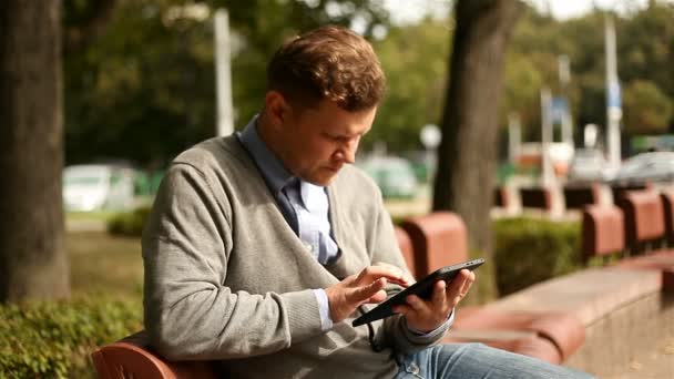 Mladý podnikatel pracuje na tabletovém počítači v městském parku — Stock video