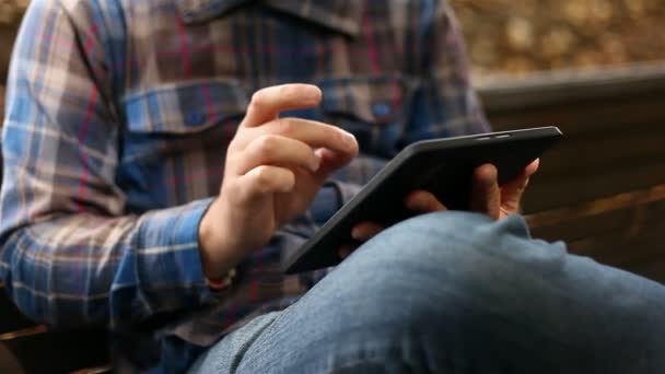 Młody mężczyzna pracujący na komputerze typu tablet w parku — Wideo stockowe