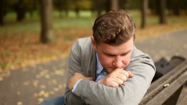 Depressief, triest jonge zakenman zitten in het park — Stockvideo