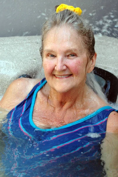 在外面的天井甲板上的热浴缸里 成熟的老年女性正在放松 — 图库照片