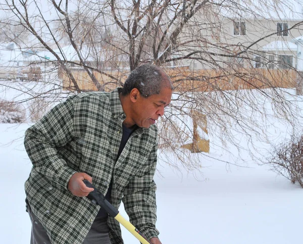 アフリカ系アメリカ人男性シニアシャベル冬の雪外 — ストック写真