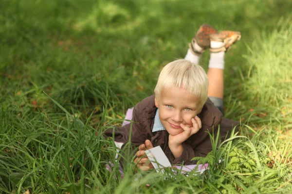 6-jähriger blonder Junge liest Buch und träumt — Stockfoto