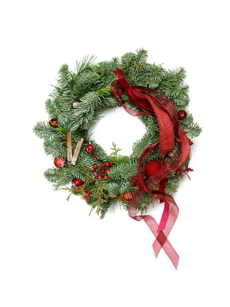 Çam iğnelerinin Noel çelengi kırmızı renklerle süslenmiş.