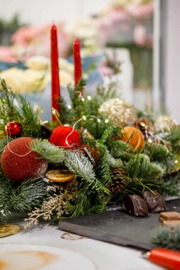 Noel dekorunun unsurları; balolarla süslenmiş mumlarla süslenmiş Noel çelengi ve Noel ağacı süslemeleri