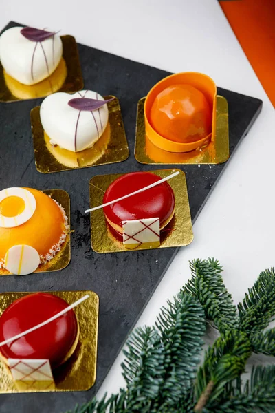 Een Tafel Met Zoetigheden Mousse Cakes Van Verschillende Vormen Kleuren — Stockfoto