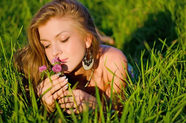 La fille est assise dans une herbe avec un panier sur un coucher de soleil — Photo