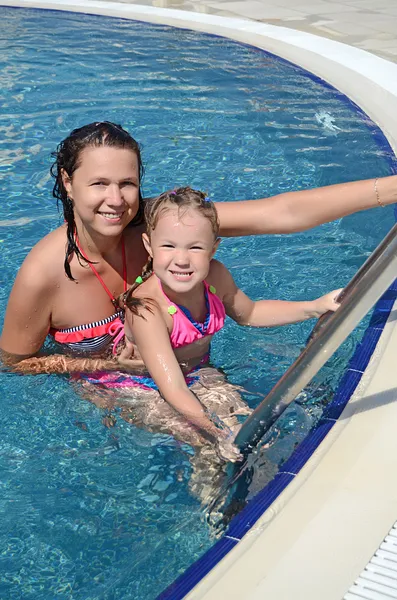 Sorrindo mulher bonita e sua filhinha fofa se divertir na piscina ao ar livre — Fotografia de Stock