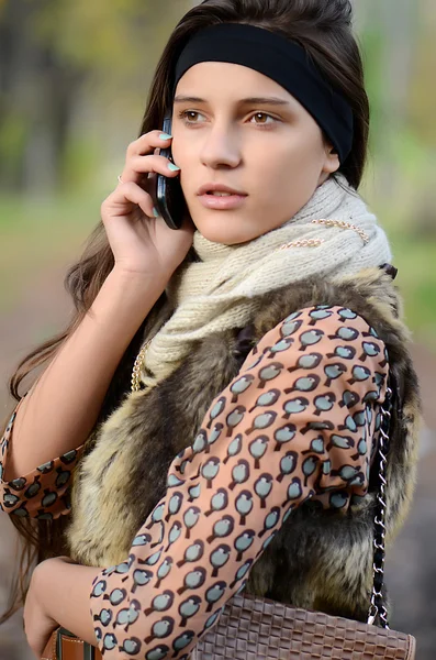 Het meisje spreekt via de telefoon in de herfst — Stockfoto