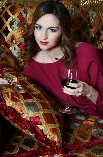 Mulher sensual com um copo de vinho tinto em um sofá magnífico — Fotografia de Stock