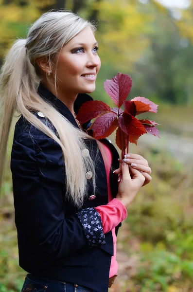 Den vackra unga kvinnan med hösten lämnar i händer — Stockfoto