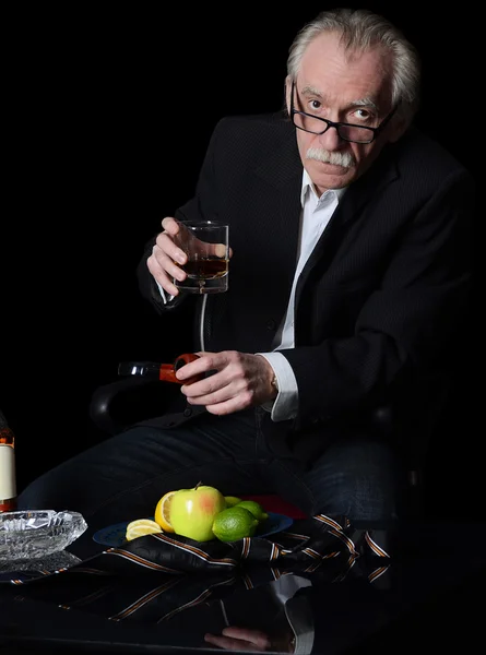 Starší muž se sklenkou whisky na černém pozadí — Stock fotografie