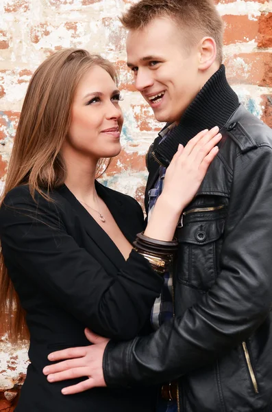 Joven pareja enamorada una pared de ladrillo — Foto de Stock