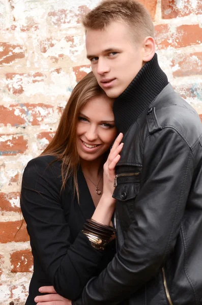 Joven pareja enamorada una pared de ladrillo — Foto de Stock