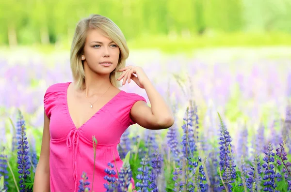 De mooie vrouw in het veld met lupin — Stockfoto