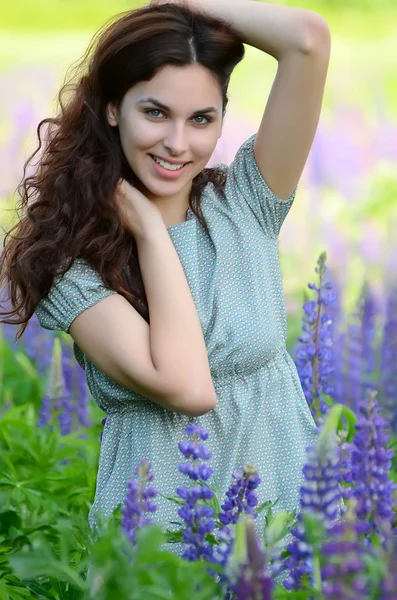 De mooie vrouw in het veld met lupin — Stockfoto