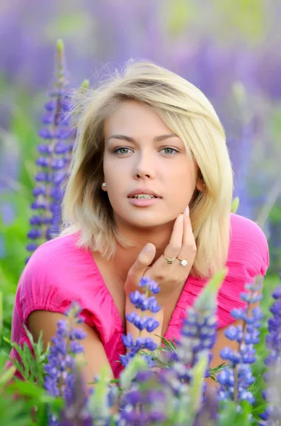 De mooie vrouw in het veld met lupin — Stockfoto