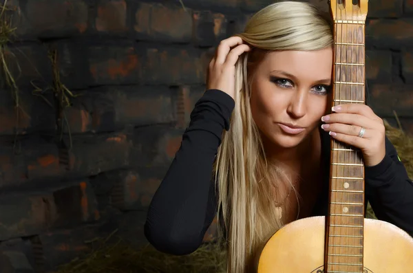 De mooie vrouw in een schuur op een muur — Stockfoto